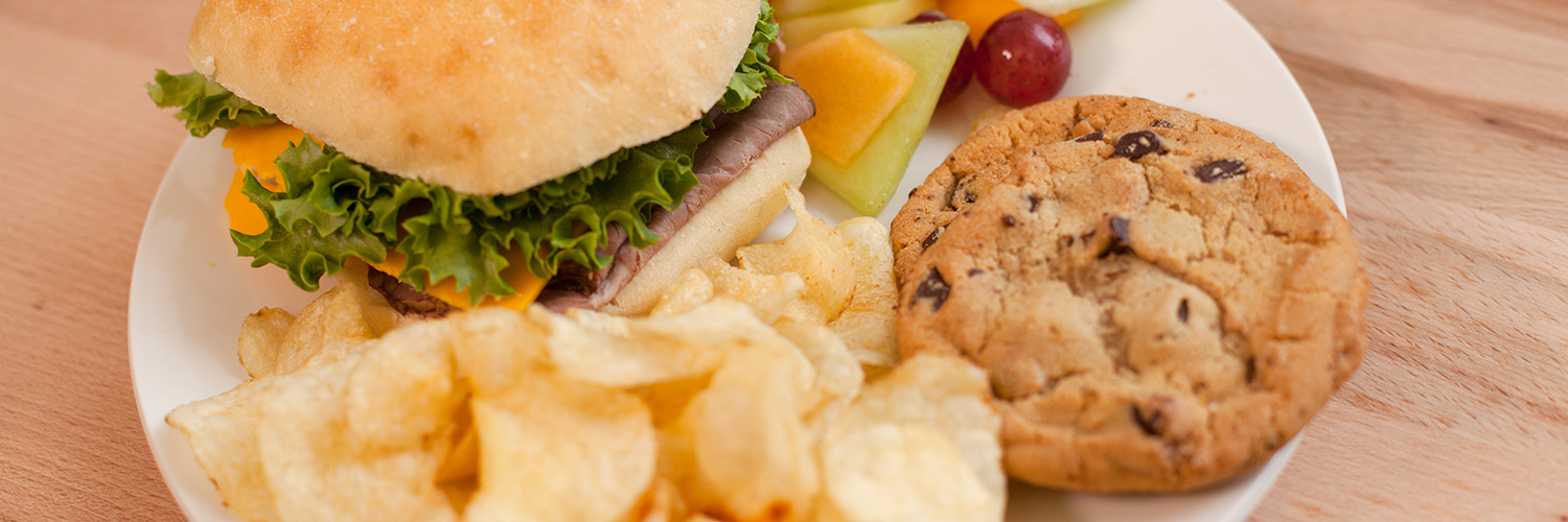 A sandwich, cookie, chips, and fruit.
