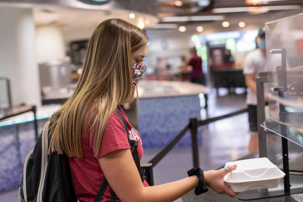 A student wearing a mask picks up a to-go order at Southside Cafe.
