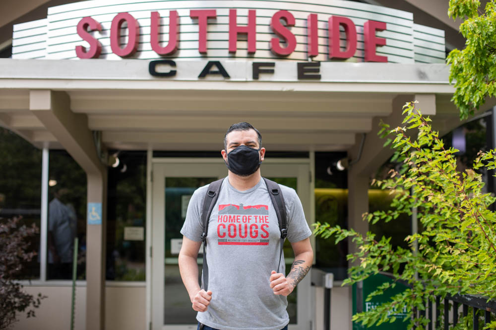 A student wearing a mask stands outside Southside Cafe.