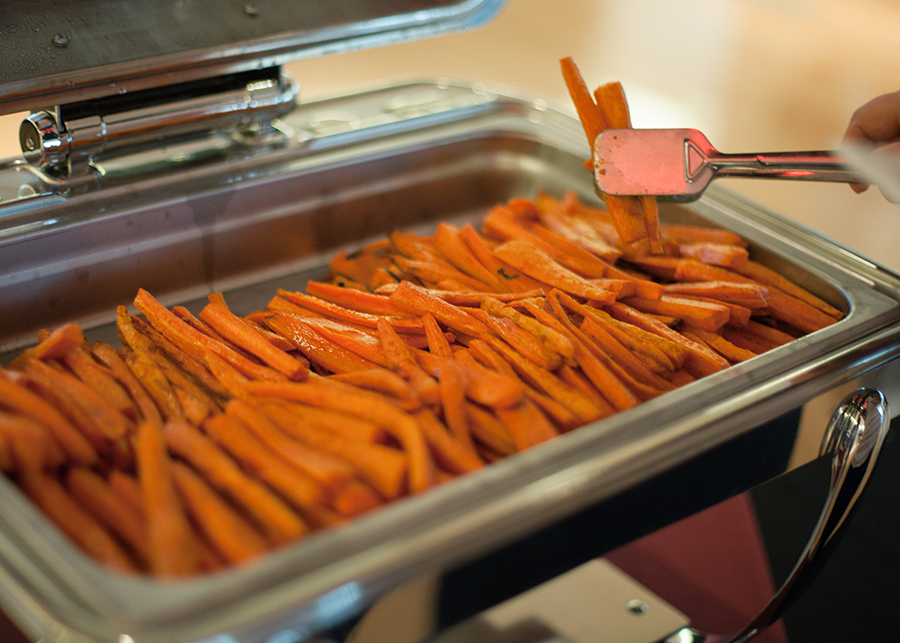 Sweet potato fries being served in a buffet.