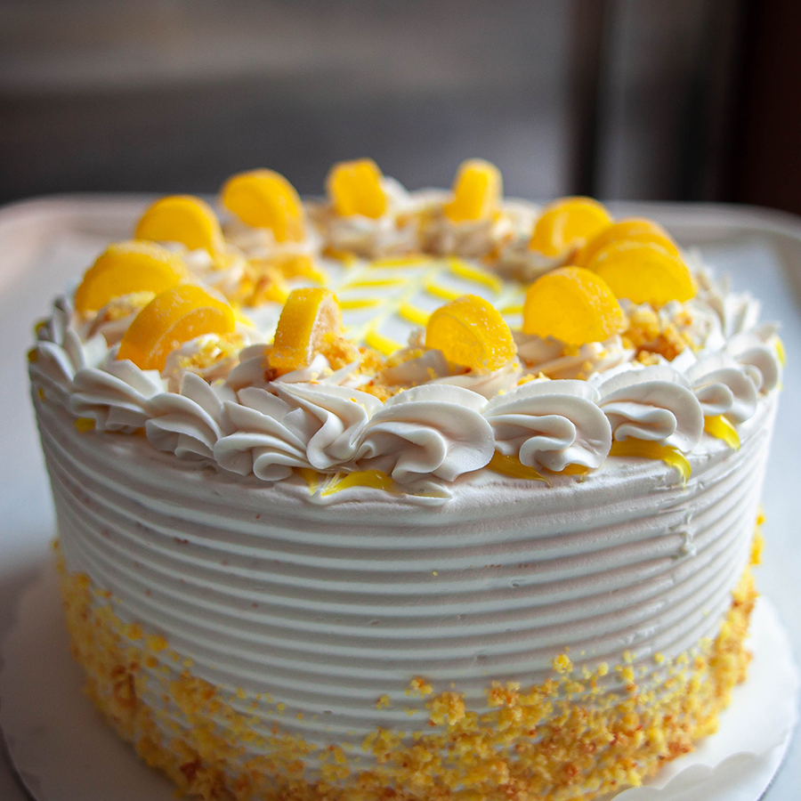A round cake with candy lemons on top.